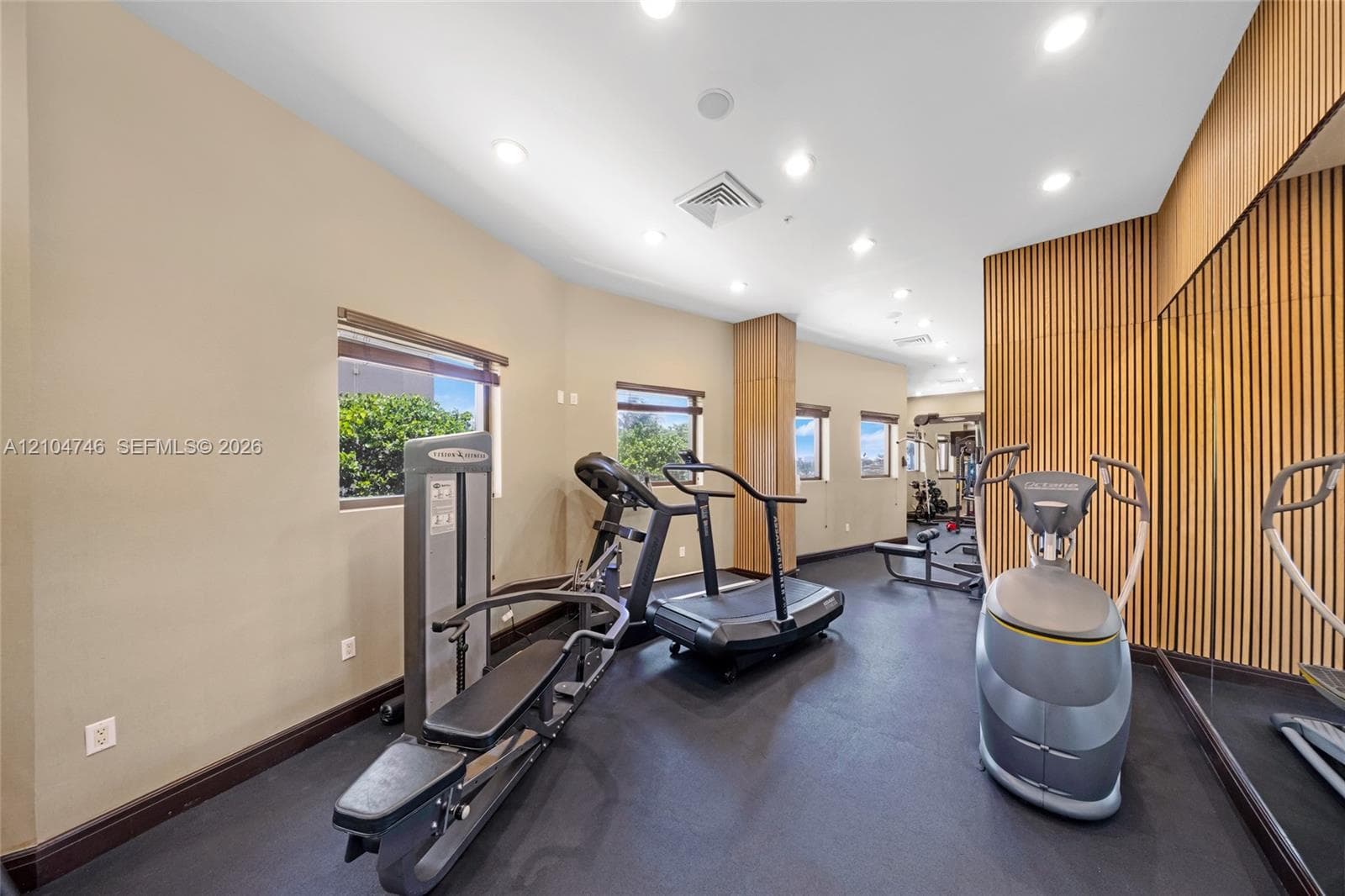 Sauna featuring horizontal wood paneling, multi-level tiered benches, and a metal heating unit, complemented by an exterior stone-veneer accent wall and tile flooring