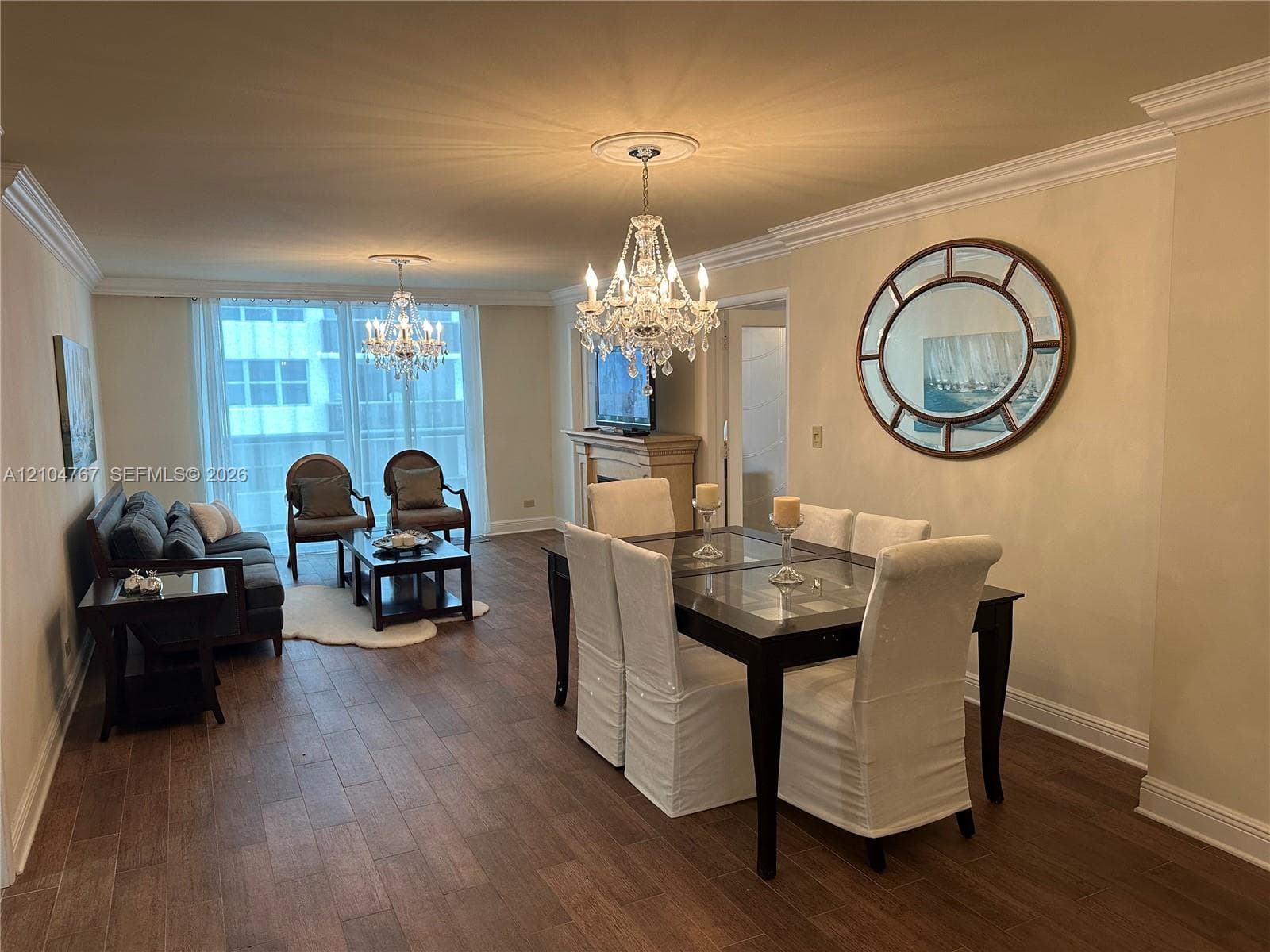 Wood-finish flooring, crown molding, tiered crystal chandeliers, and a fireplace mantle