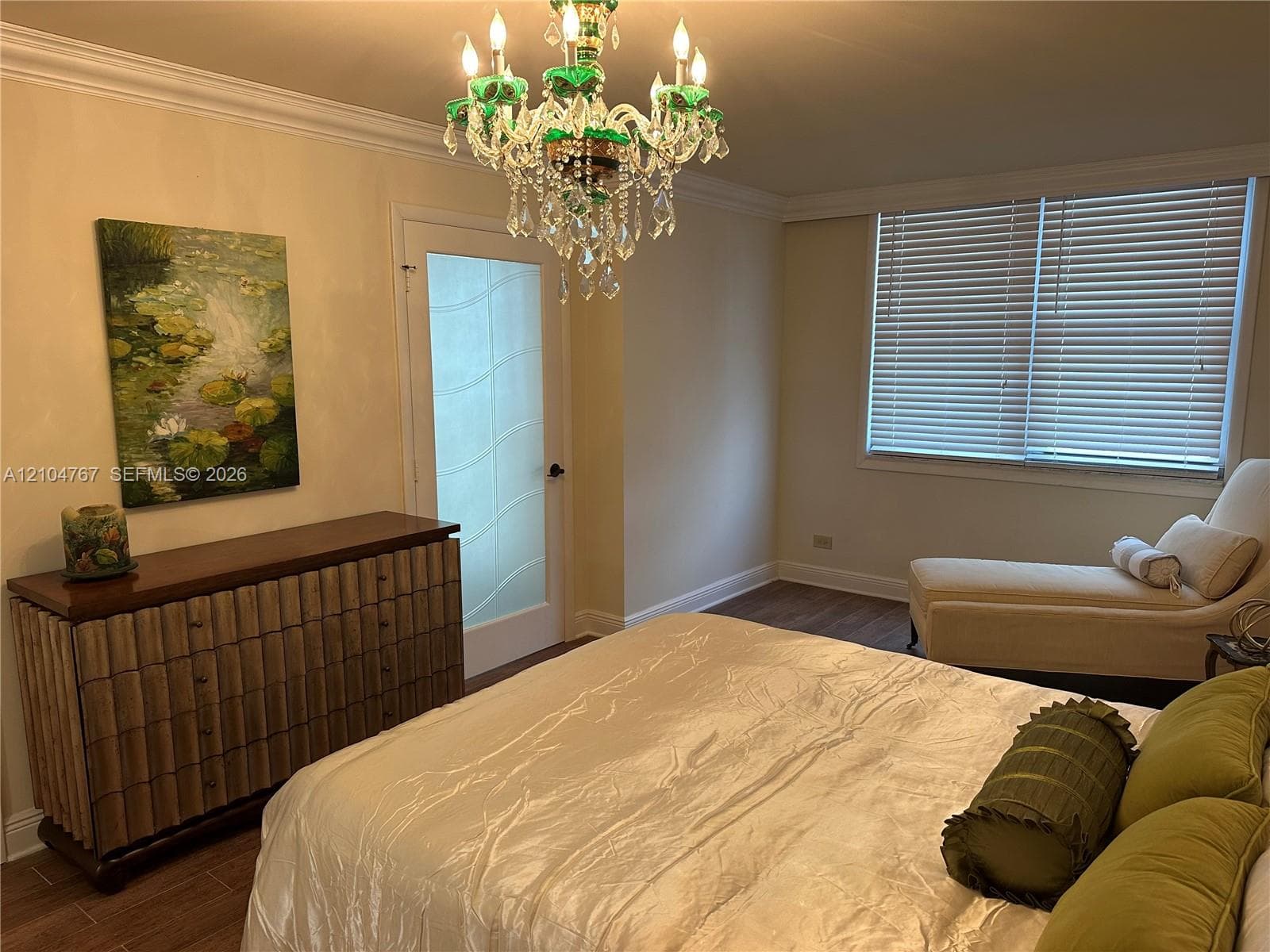 Multi-tiered crystal chandelier with green glass accents, wood-finish flooring, and single-panel door with frosted glass inlay