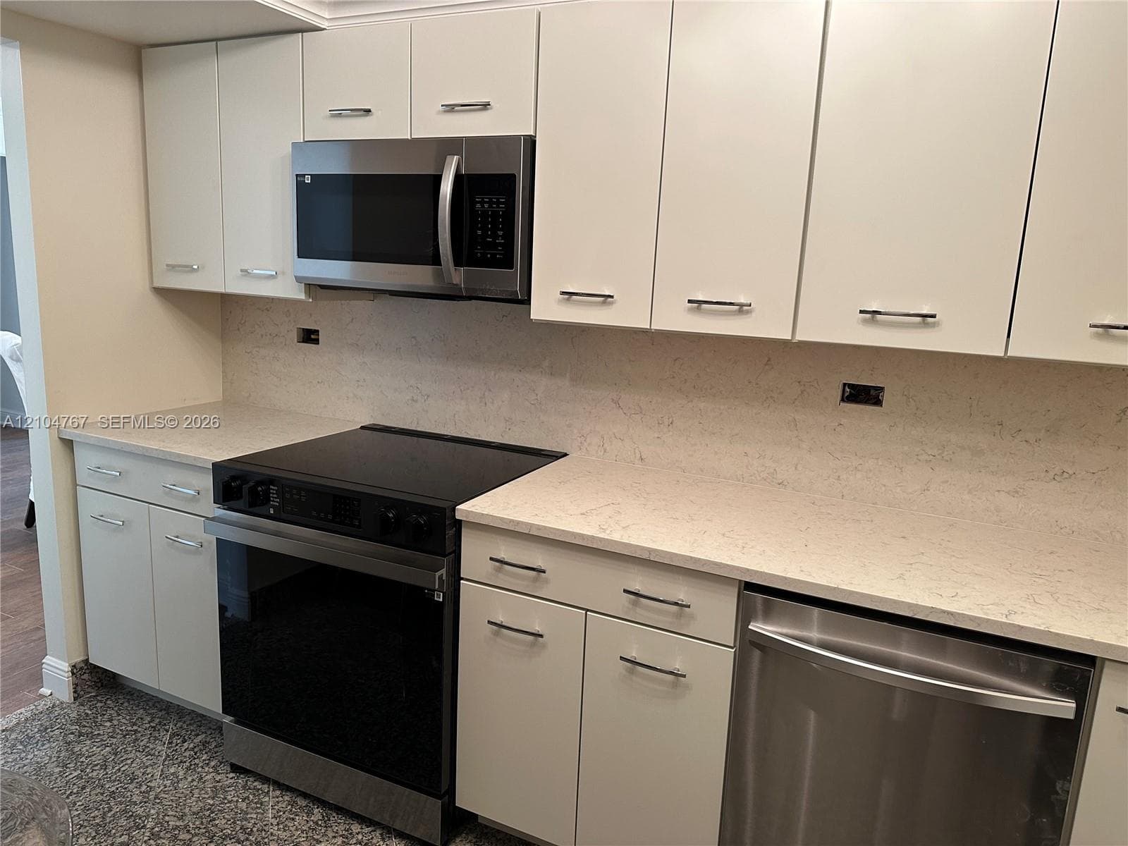 Kitchen featuring flat-panel cabinetry, light-toned stone-finish countertops, stainless steel appliances, and crown molding