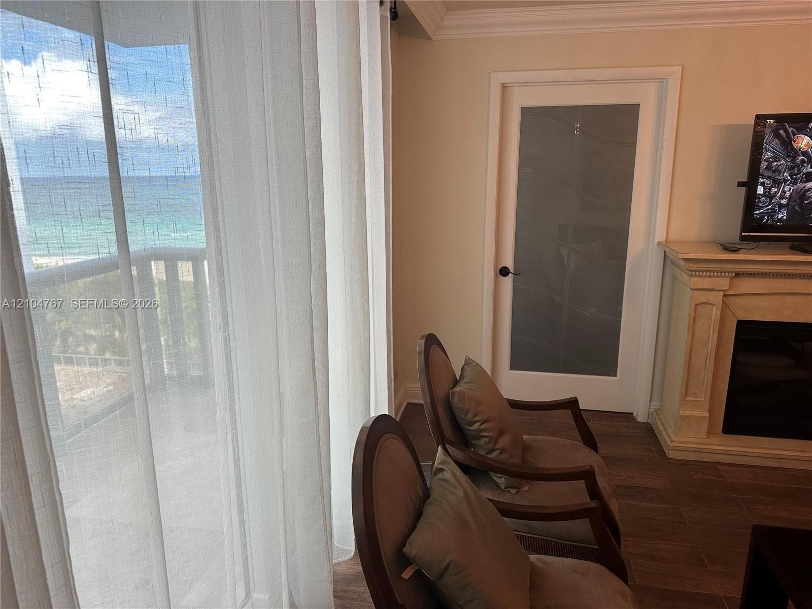 Floor-to-ceiling glass sliding doors, wood-finish flooring, built-in fireplace with detailed mantle, and interior door with frosted glass panel