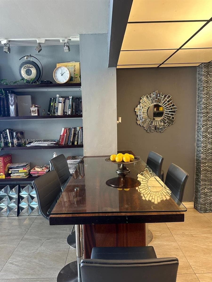 Built-in track lighting, integrated wall shelving, wood-finish dining surface with glass top, full-height decorative wall paneling, and a unique ceiling light fixture