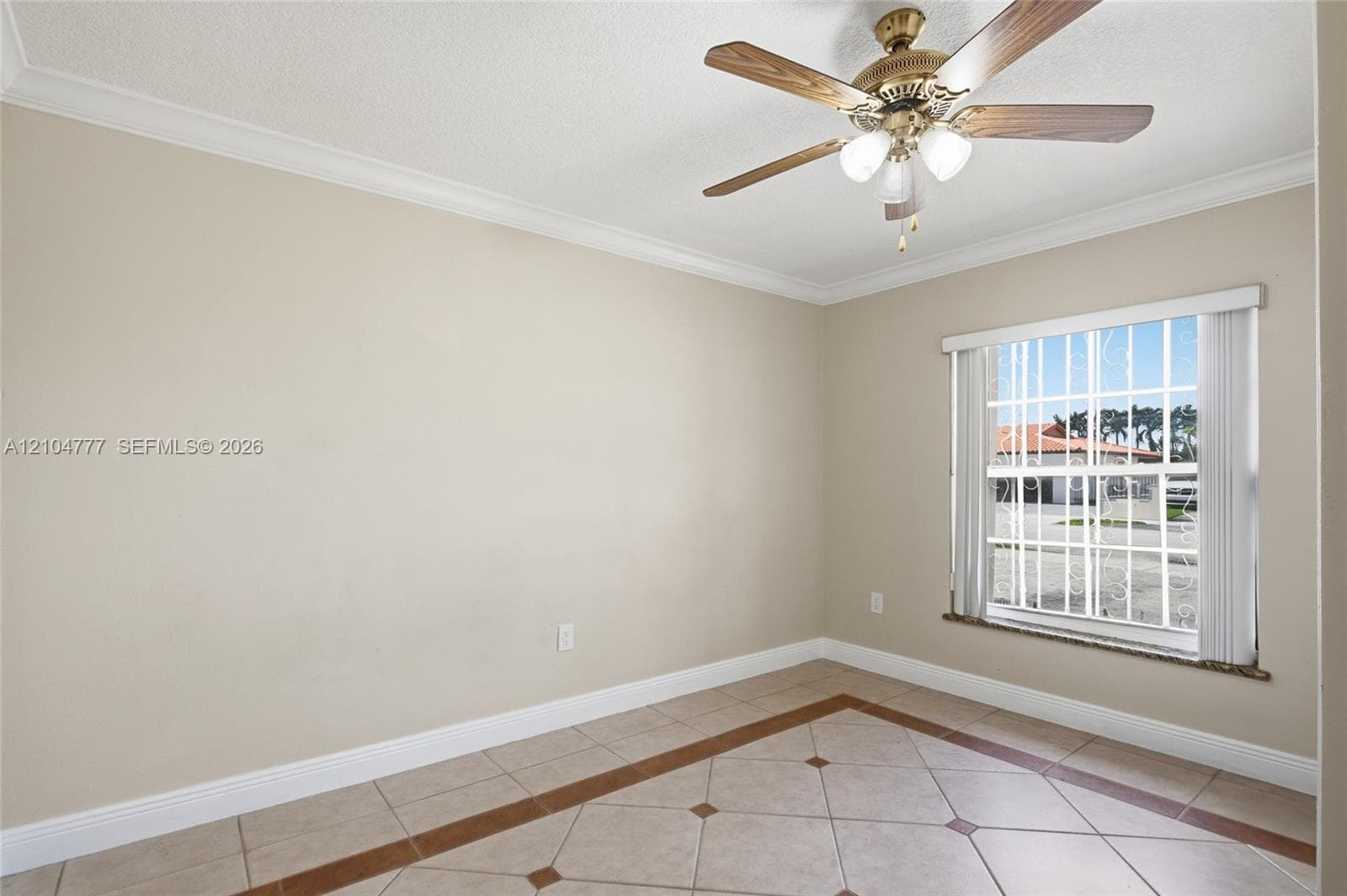 Tile flooring with a decorative inlay, crown molding, and a ceiling fan with integrated lighting