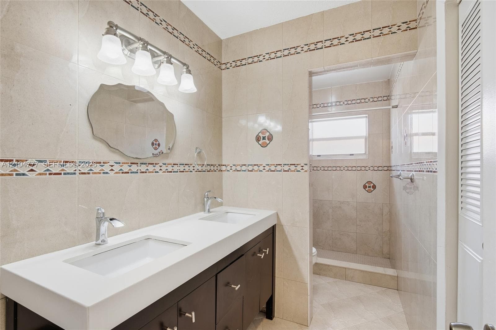 Double vanity with integrated sinks, chrome fixtures, and a dark wood-finish cabinet