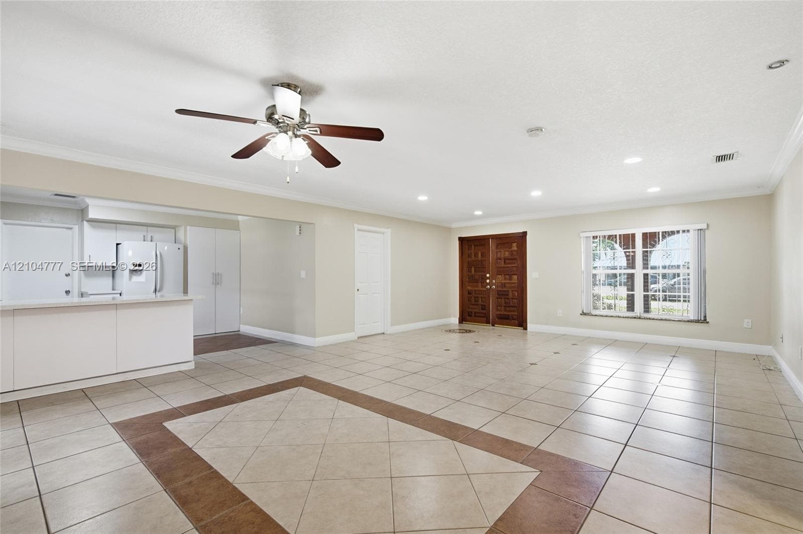 Spacious open-concept room featuring a ceiling fan, recessed lighting, and tile flooring with an inlaid pattern