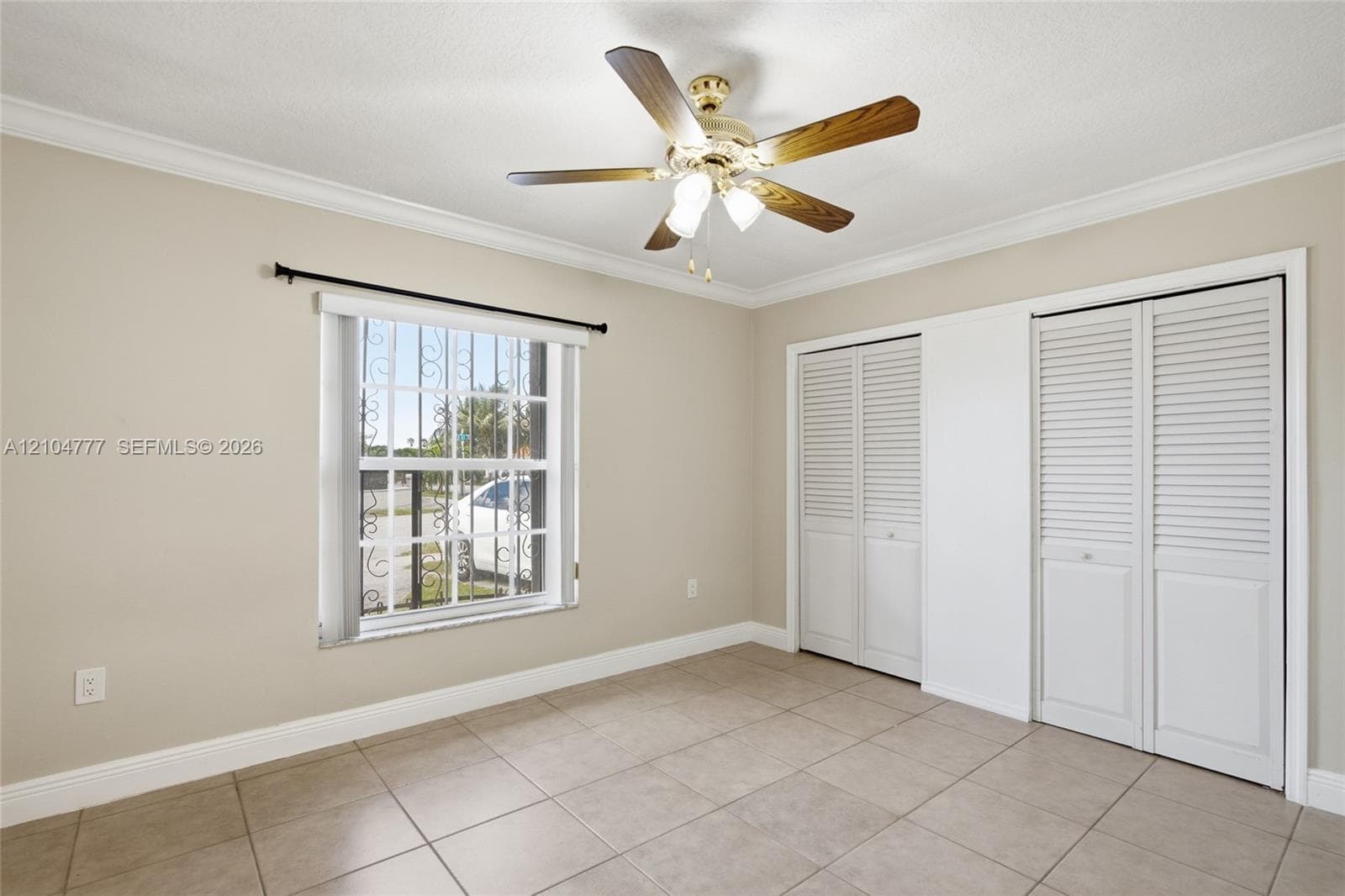 Recessed lighting fixture, crown molding, ceiling fan, tile flooring, and louvered bi-fold closet doors