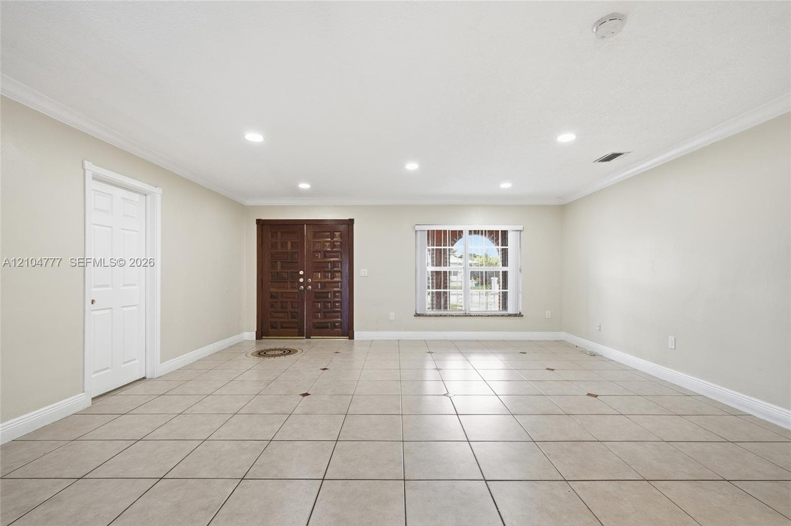 Recessed lighting, crown molding, double entry doors with decorative panels, large window with blinds, and tile flooring