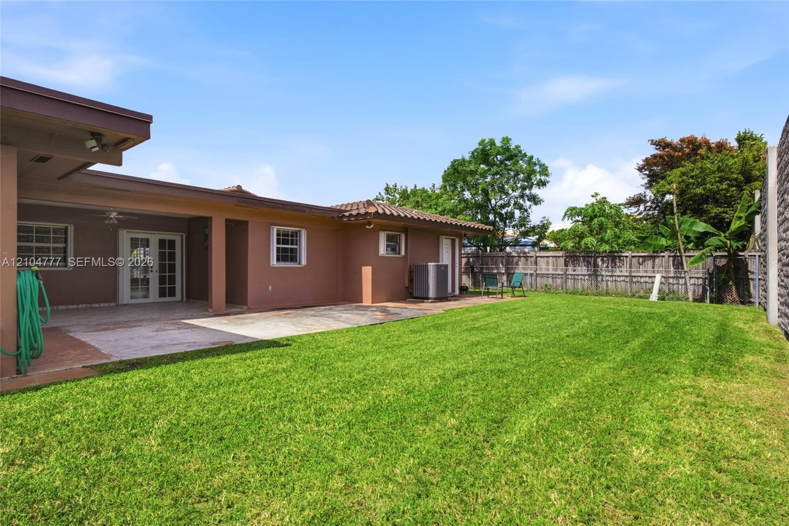 Expansive backyard featuring a manicured lawn, a large covered patio, and a privacy fence