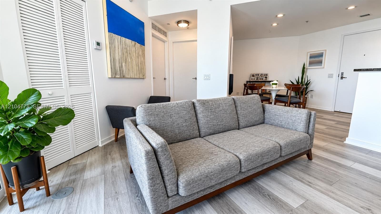 Light wood-finish flooring throughout, white louvered bifold doors, recessed lighting, and white interior doors