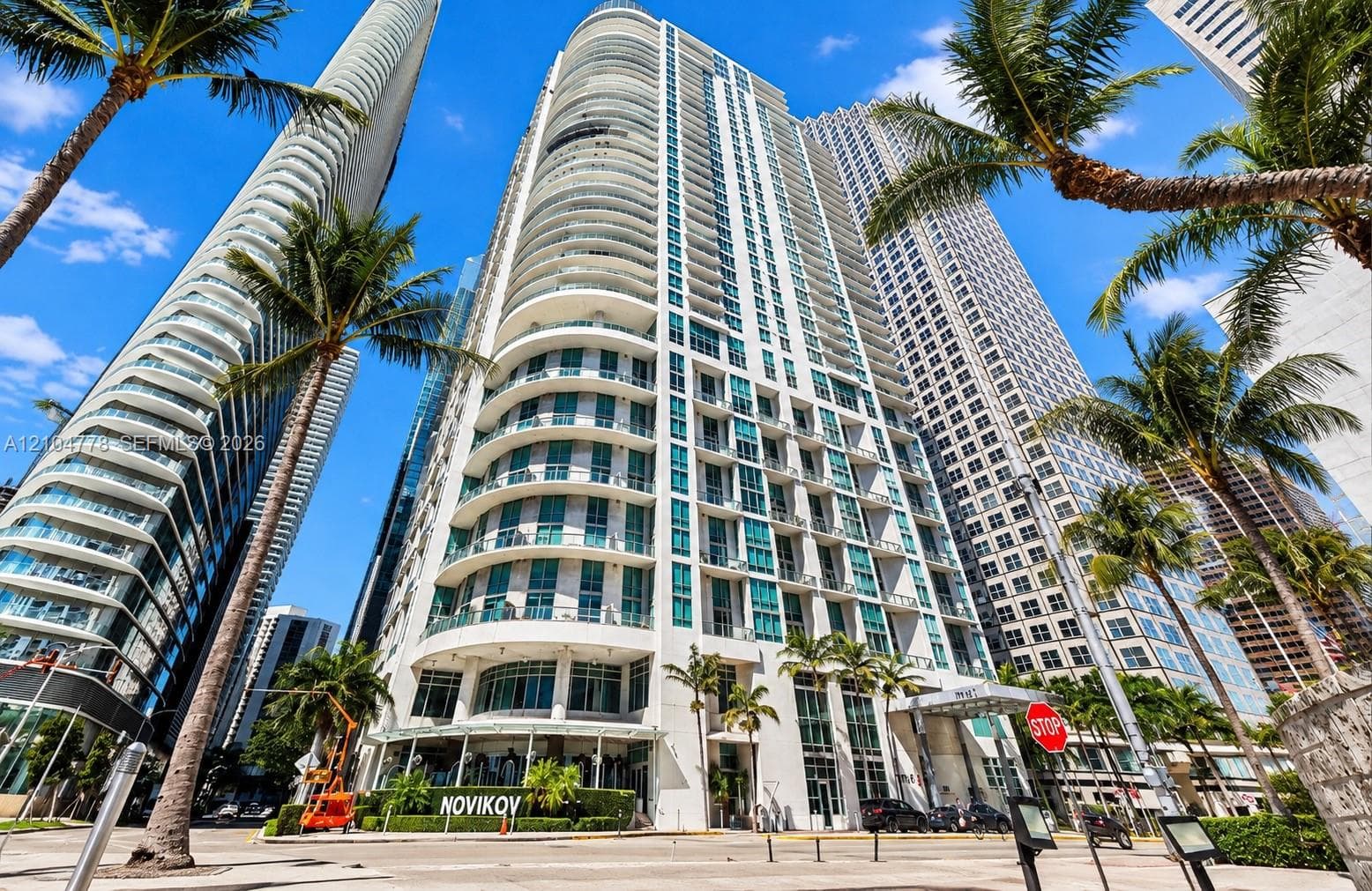 Modern high-rise architecture with curved balconies, floor-to-ceiling windows, and a prominent ground-floor retail space