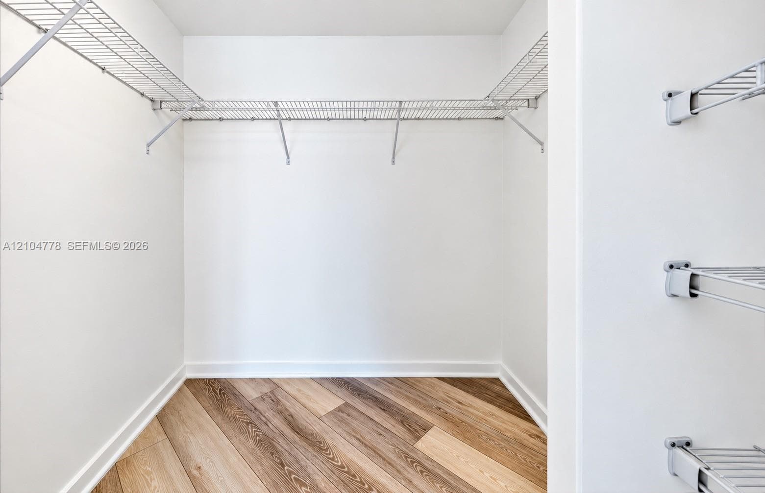 Walk-in closet with wire shelving system and wood-finish flooring
