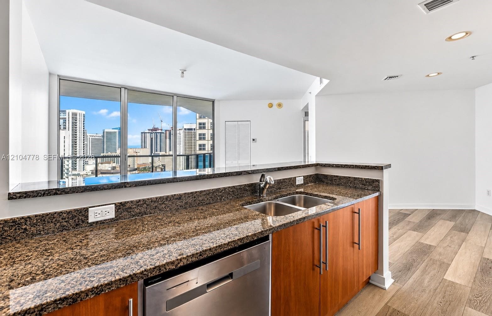 Kitchen featuring stone countertops, a double basin stainless steel sink, wood-finish cabinetry, and an integrated stainless steel dishwasher