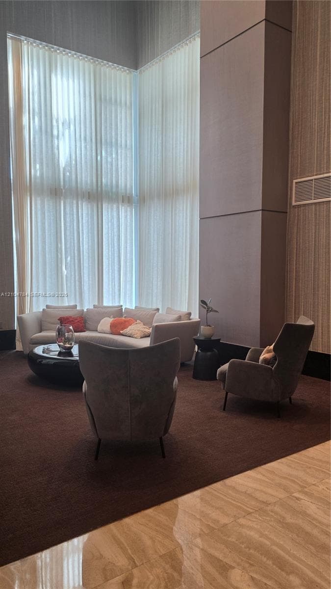 Double-height floor-to-ceiling windows, soaring vertical wall panels, and polished stone tile flooring