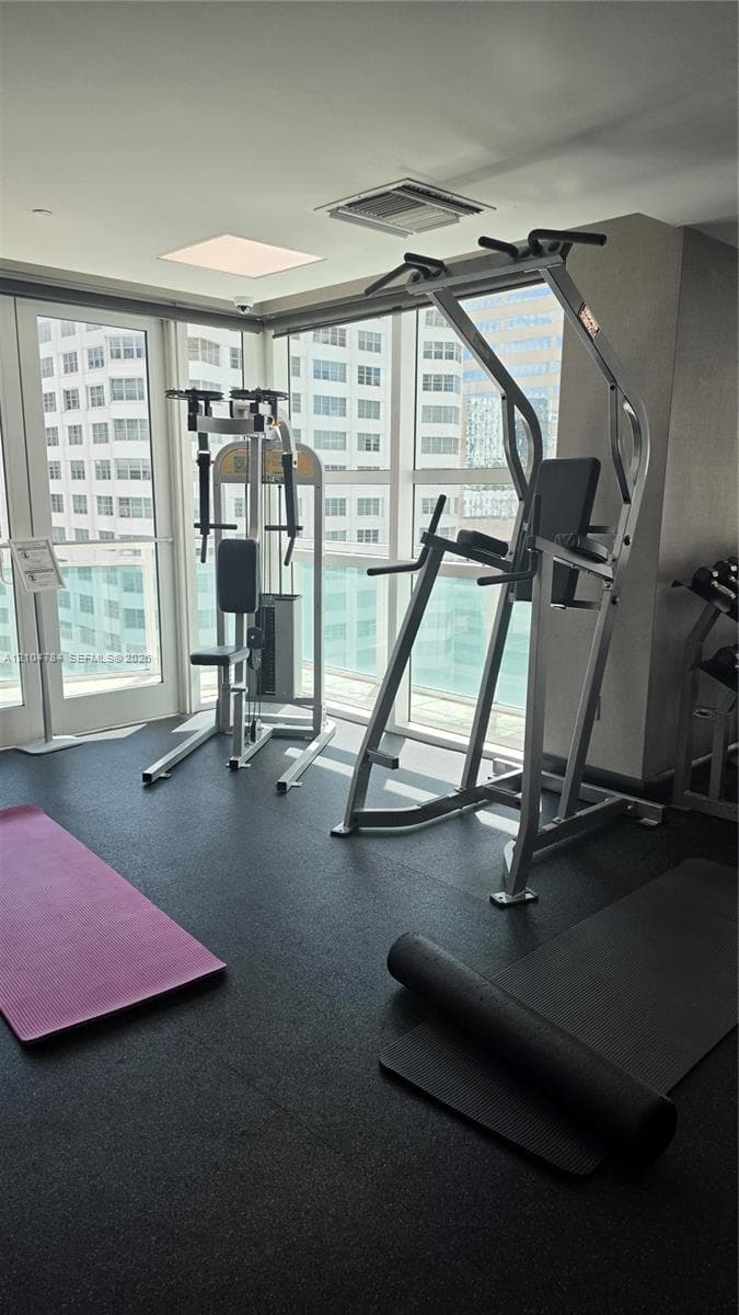 Fitness center featuring rubberized flooring, expansive floor-to-ceiling windows, and recessed ceiling lighting