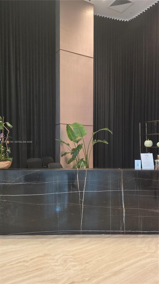 Reception desk featuring a polished dark stone surface with veining, a floor-to-ceiling accent pillar, and stone-finish flooring