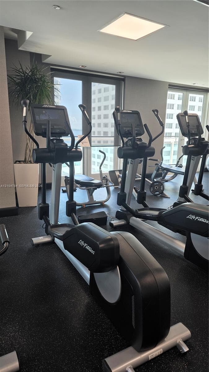 Fitness center featuring high-impact rubber flooring, recessed square ceiling lighting, and floor-to-ceiling windows