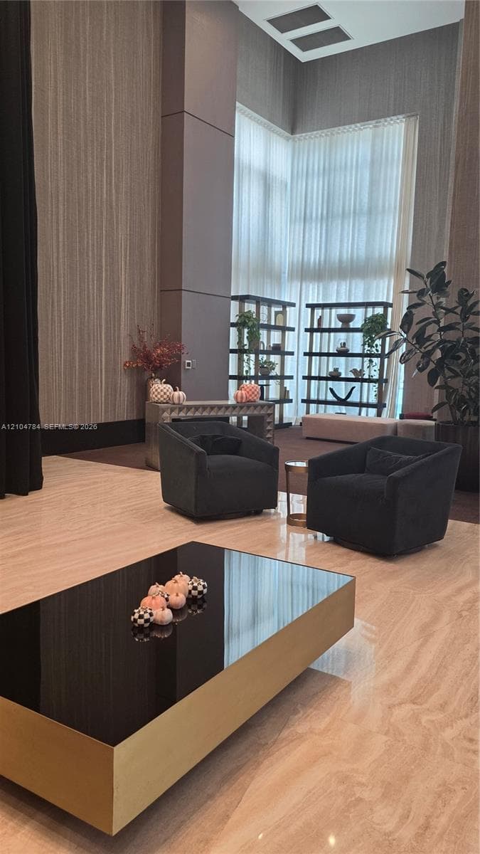 Double-height ceilings, floor-to-ceiling windows, stone-finish flooring, and built-in shelving units
