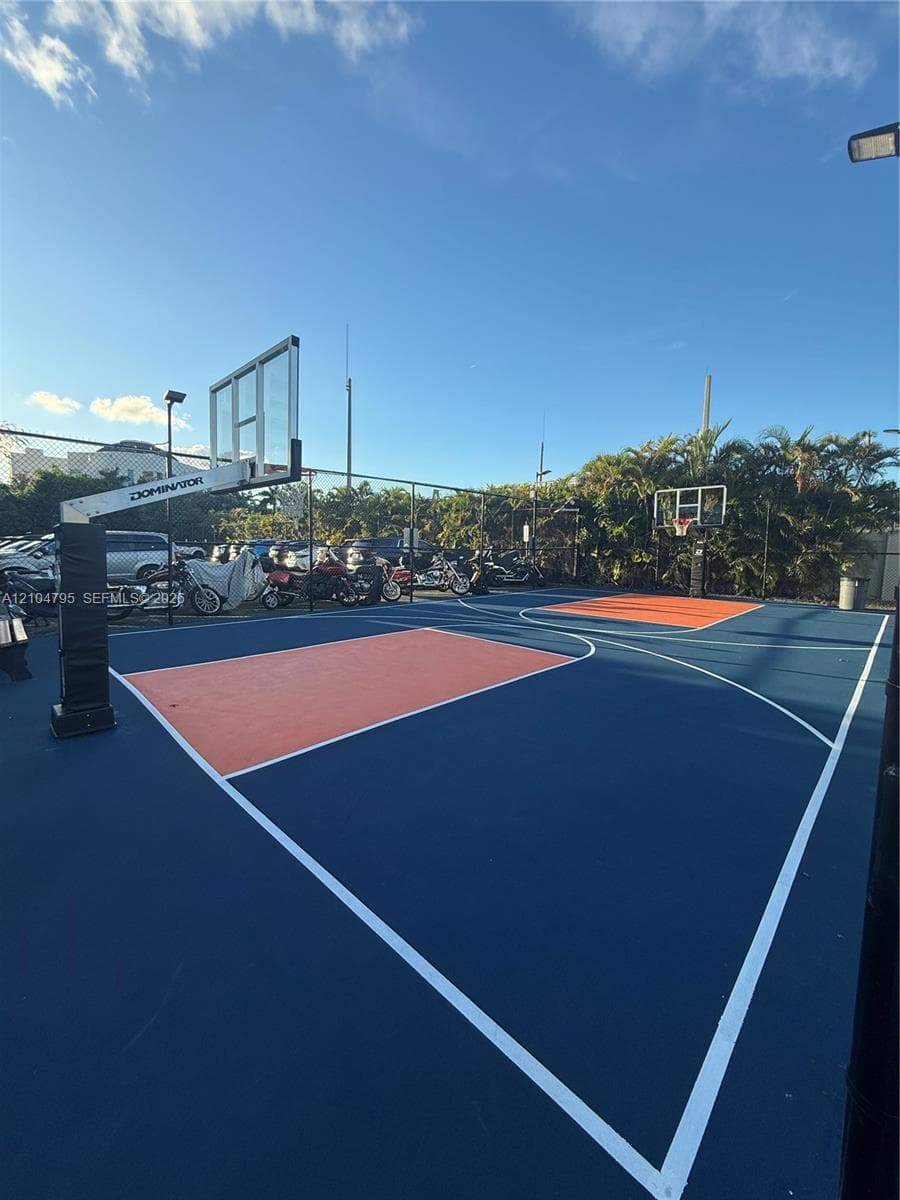 Multi-sport court featuring a synthetic blue and orange surface, two adjustable basketball hoops, and perimeter chain-link fencing