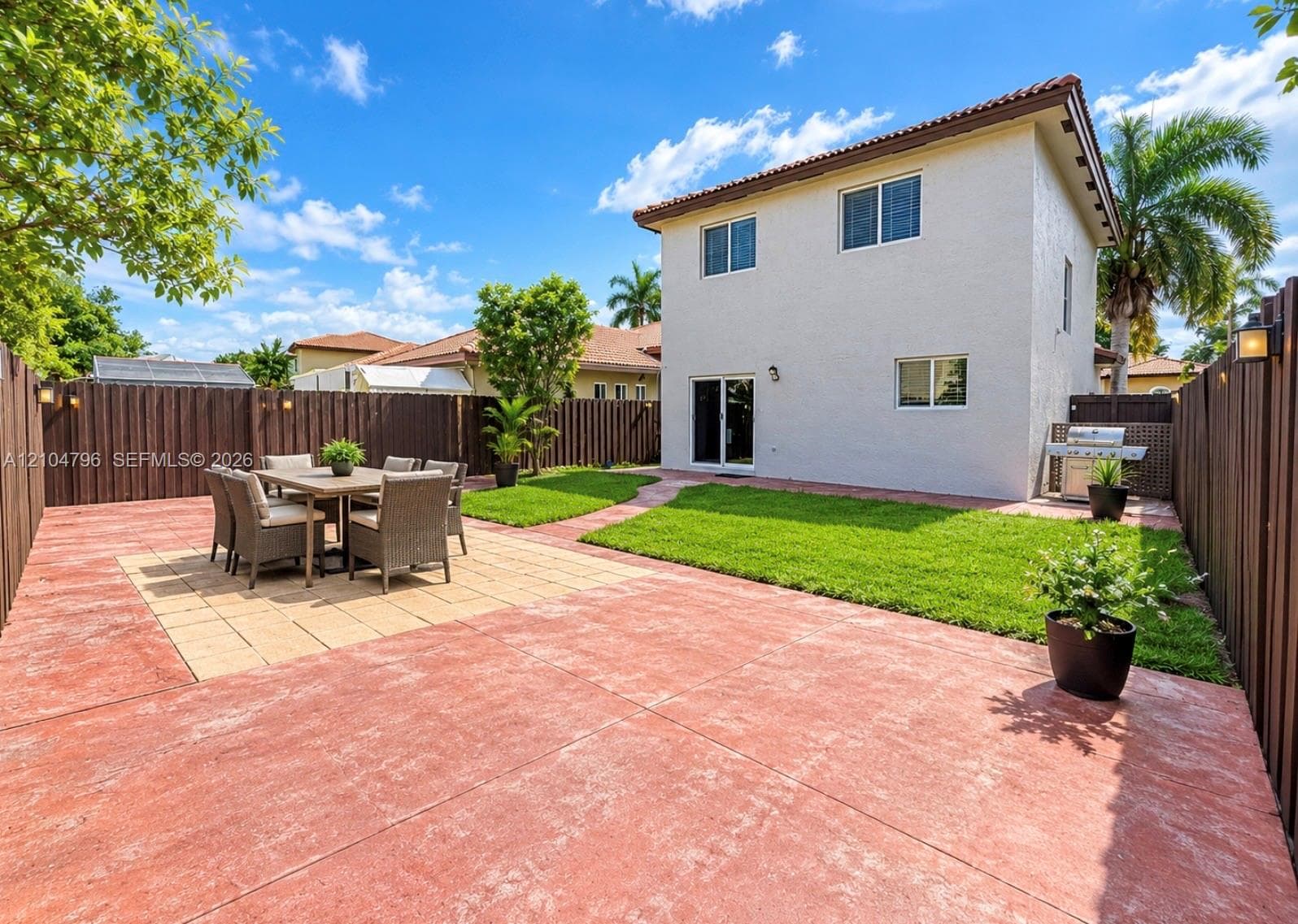 Private backyard featuring stamped concrete patio, manicured lawn, and full-height wood privacy fencing
