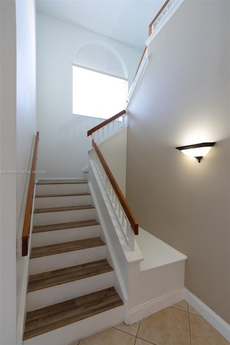 Staircase featuring wood-finish treads, white risers, and a wood handrail