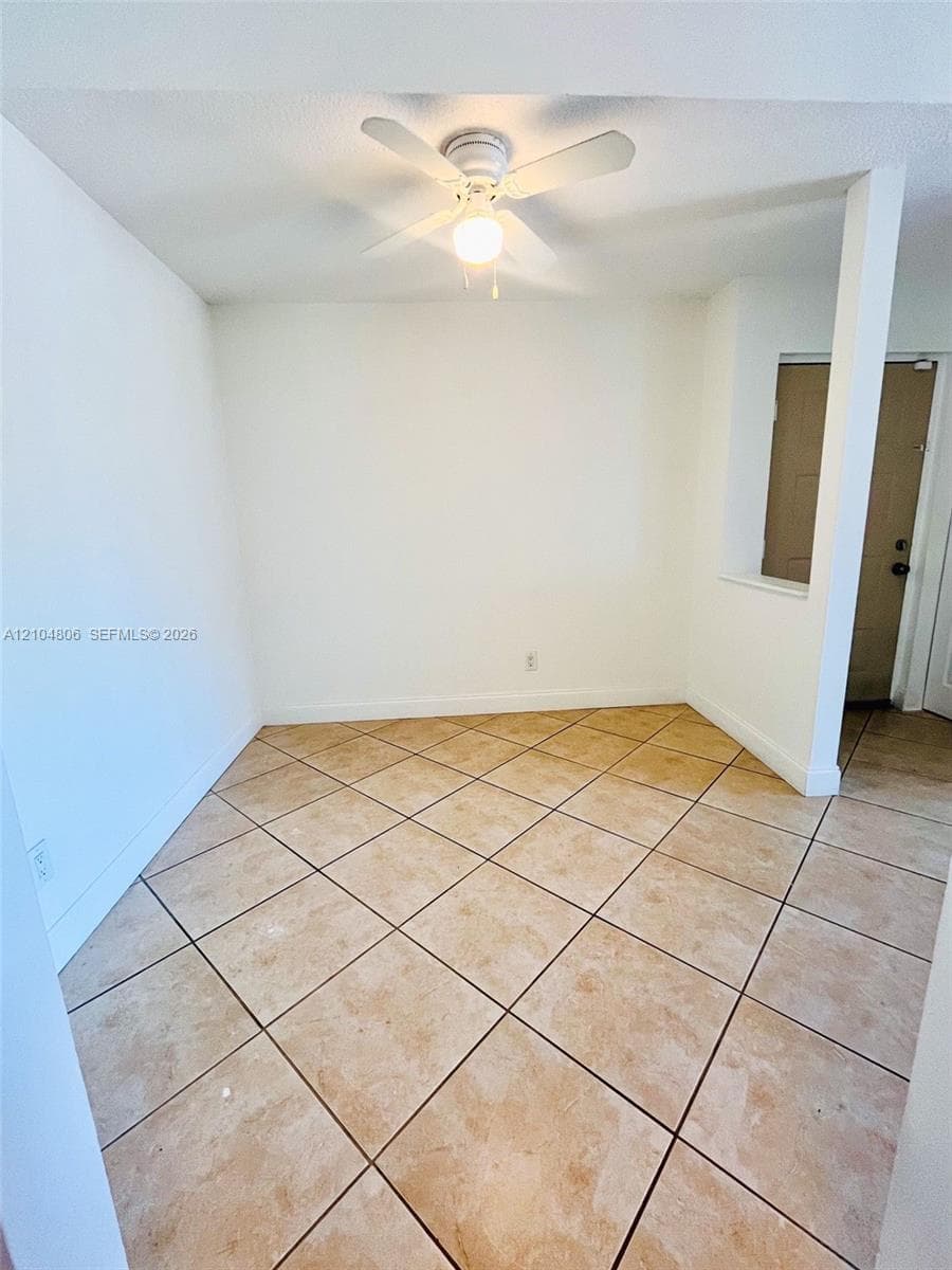 Light-toned tile flooring, white walls, and a ceiling fan with integrated lighting