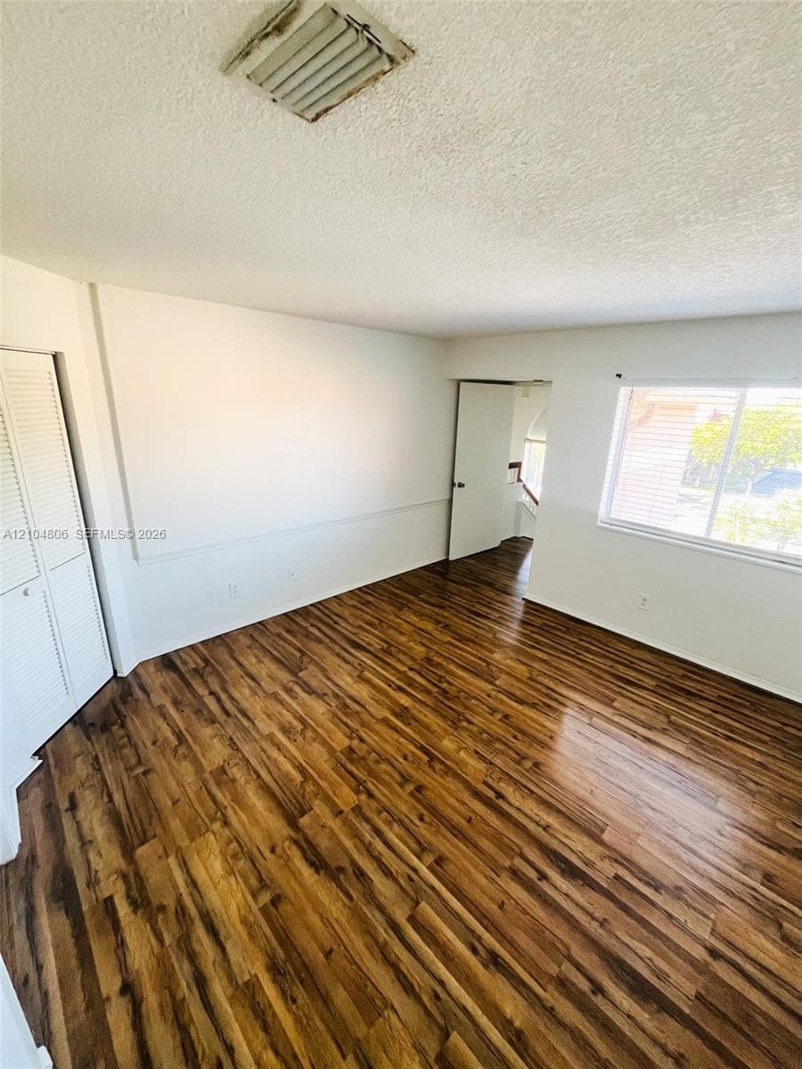 Wood-finish flooring throughout, white walls, and a window providing natural light