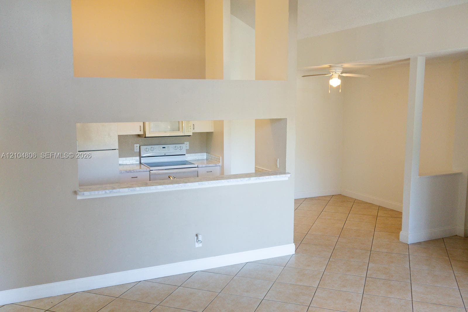 Kitchen pass-through with a breakfast bar, stainless steel range, and ceiling fan