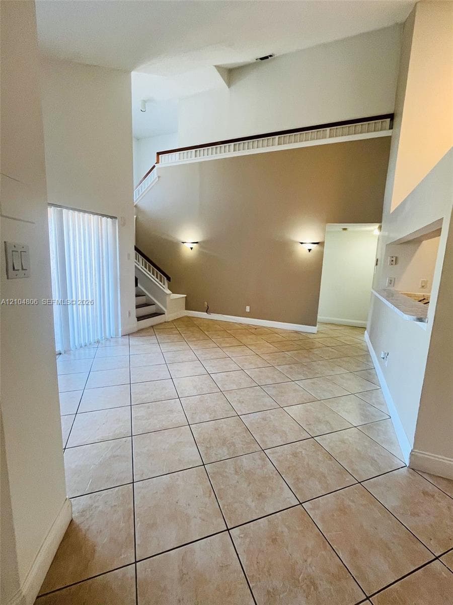High ceilings, neutral-toned walls, tile flooring, two-story architectural elements, and recessed wall lighting