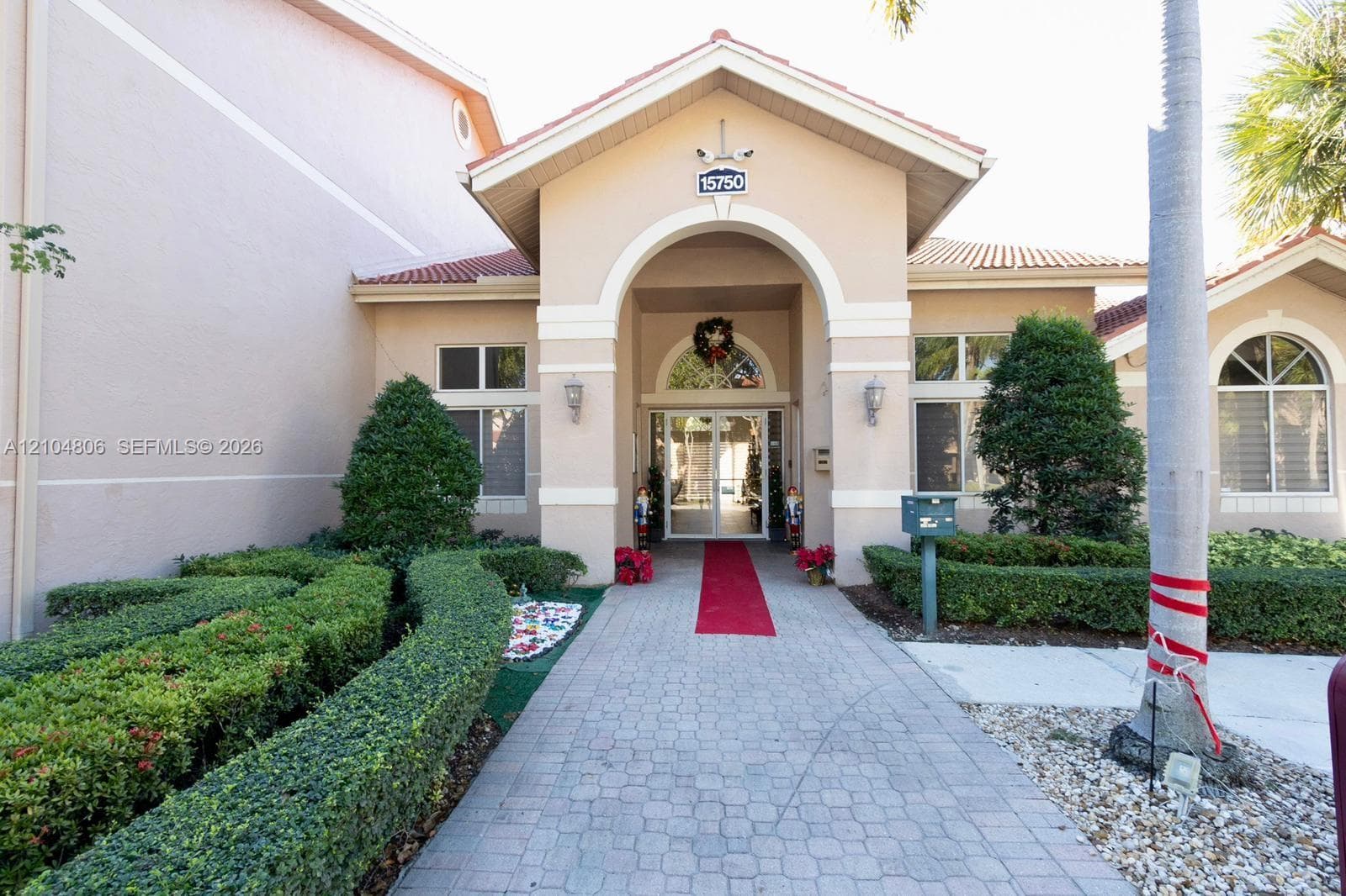 Stucco exterior with a tiled roof, arched entryway, and decorative exterior lighting