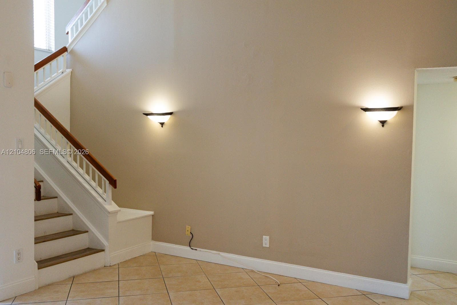 Staircase with wood handrail, white balusters, and painted risers
