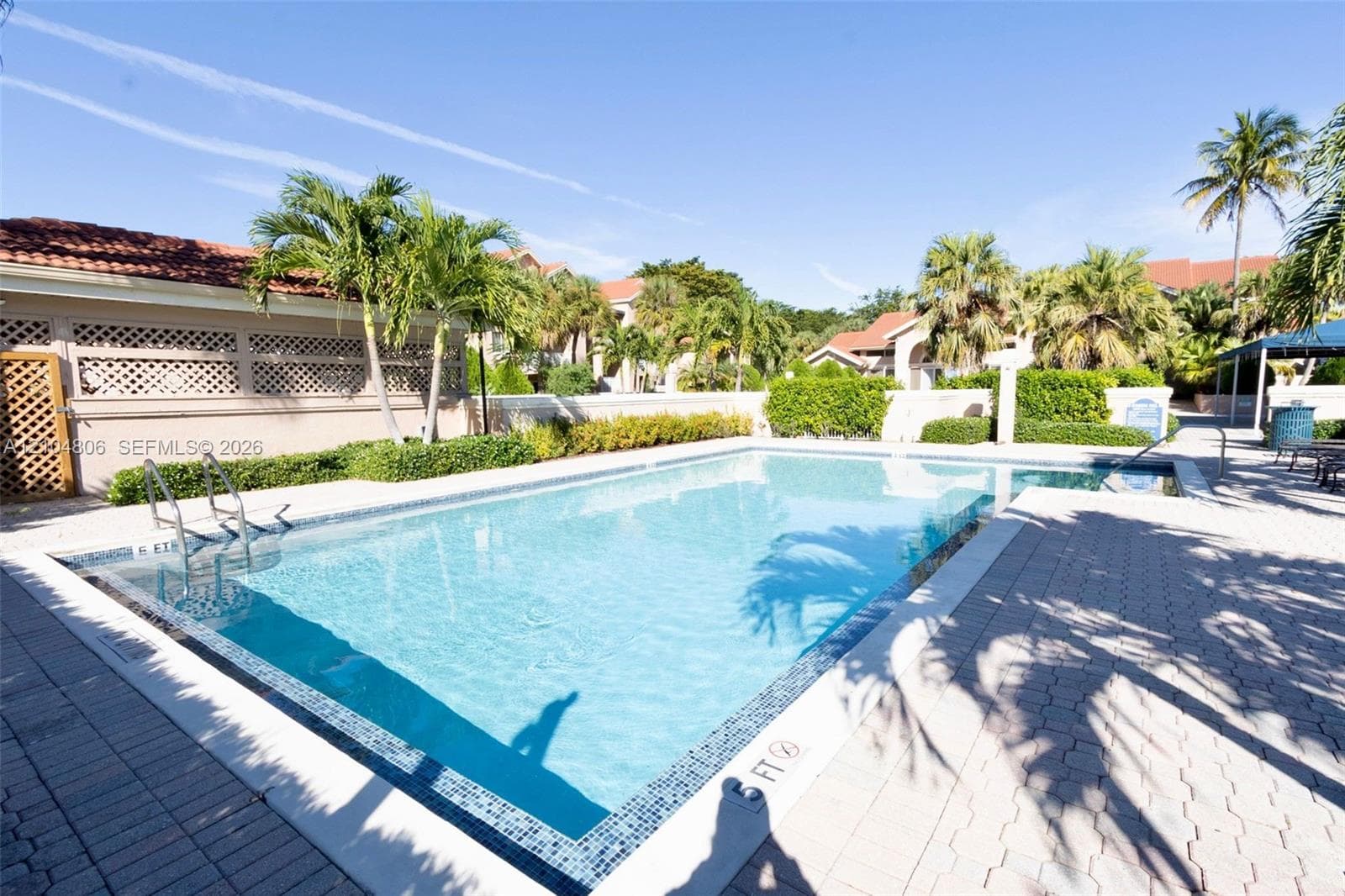 Rectangular swimming pool with mosaic tile accents, integrated spa, and surrounding paver decking