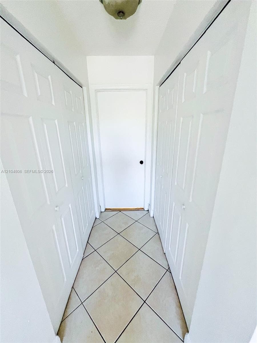 Hallway featuring ceramic tile flooring, bi-fold closet doors, and a flush mount ceiling light fixture