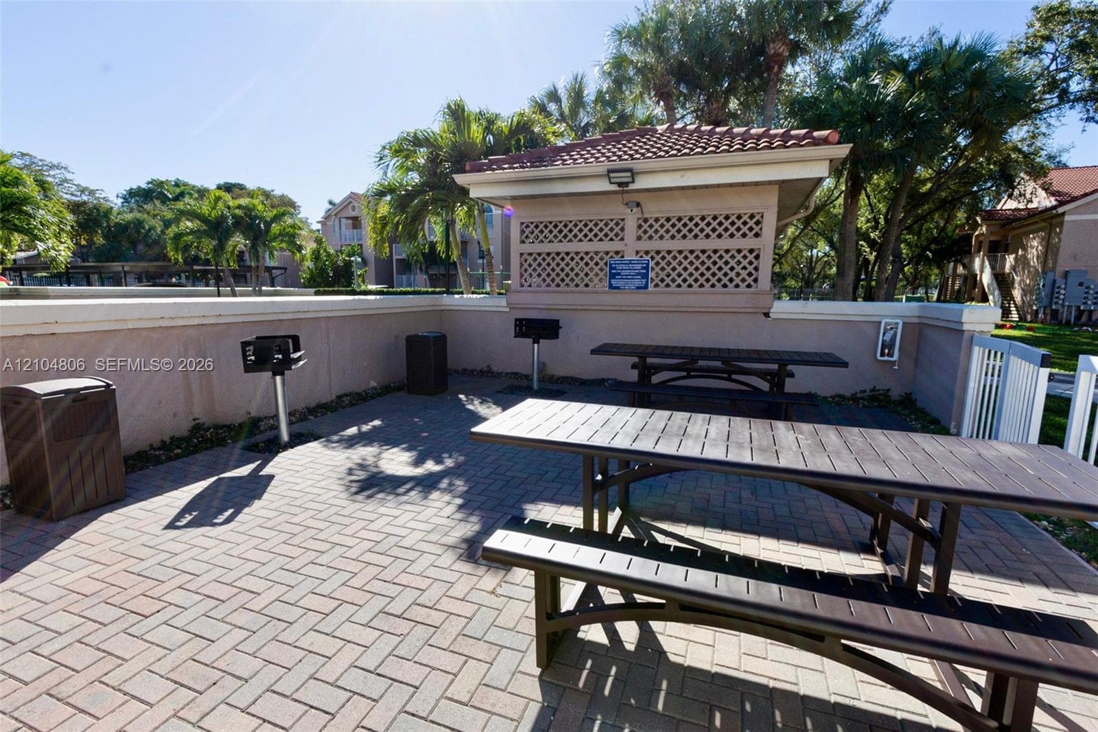 Paver patio featuring multiple picnic tables and a covered BBQ area