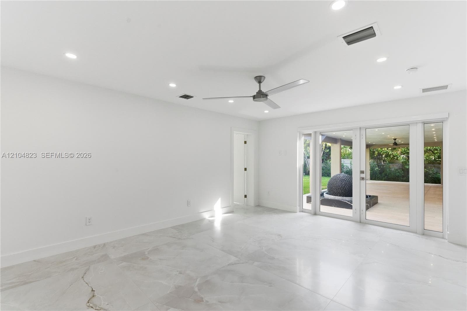 Large-format tiled flooring, recessed ceiling lighting, three-blade ceiling fan, and multi-panel glass door system