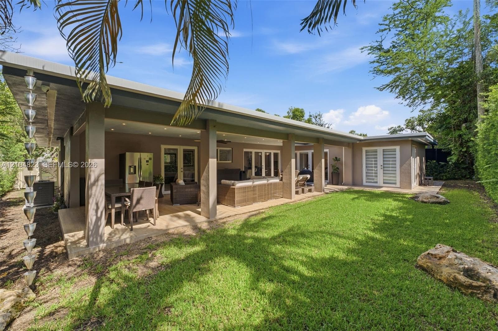 Expansive rear patio with recessed lighting and exterior ceiling fan, featuring a rain chain downspout and multiple glass panel doors