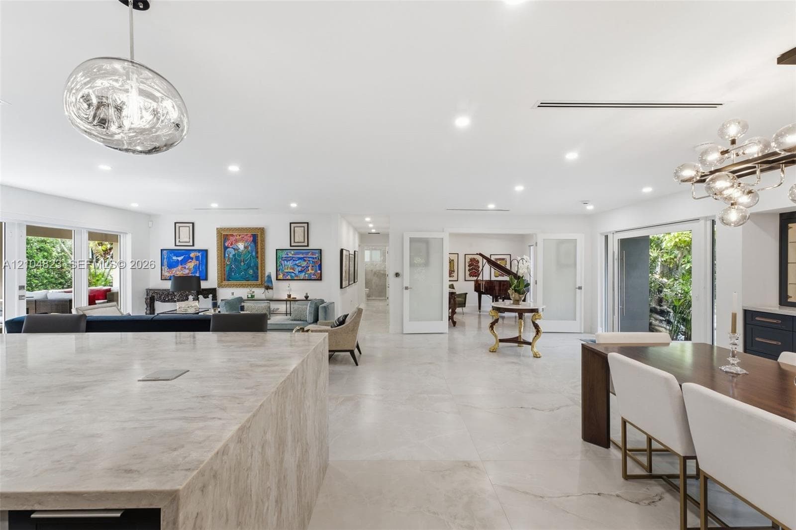 Recessed lighting throughout, wide plank tile flooring, expansive sliding glass doors, built-in cabinetry, and a contemporary chandelier