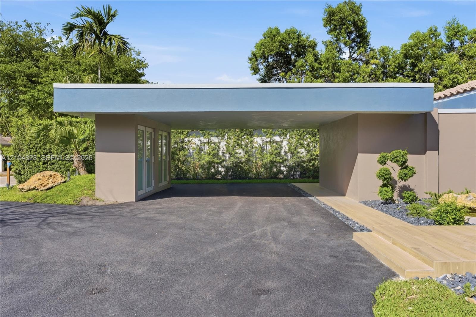 Covered entryway with asphalt driveway and modern landscaping