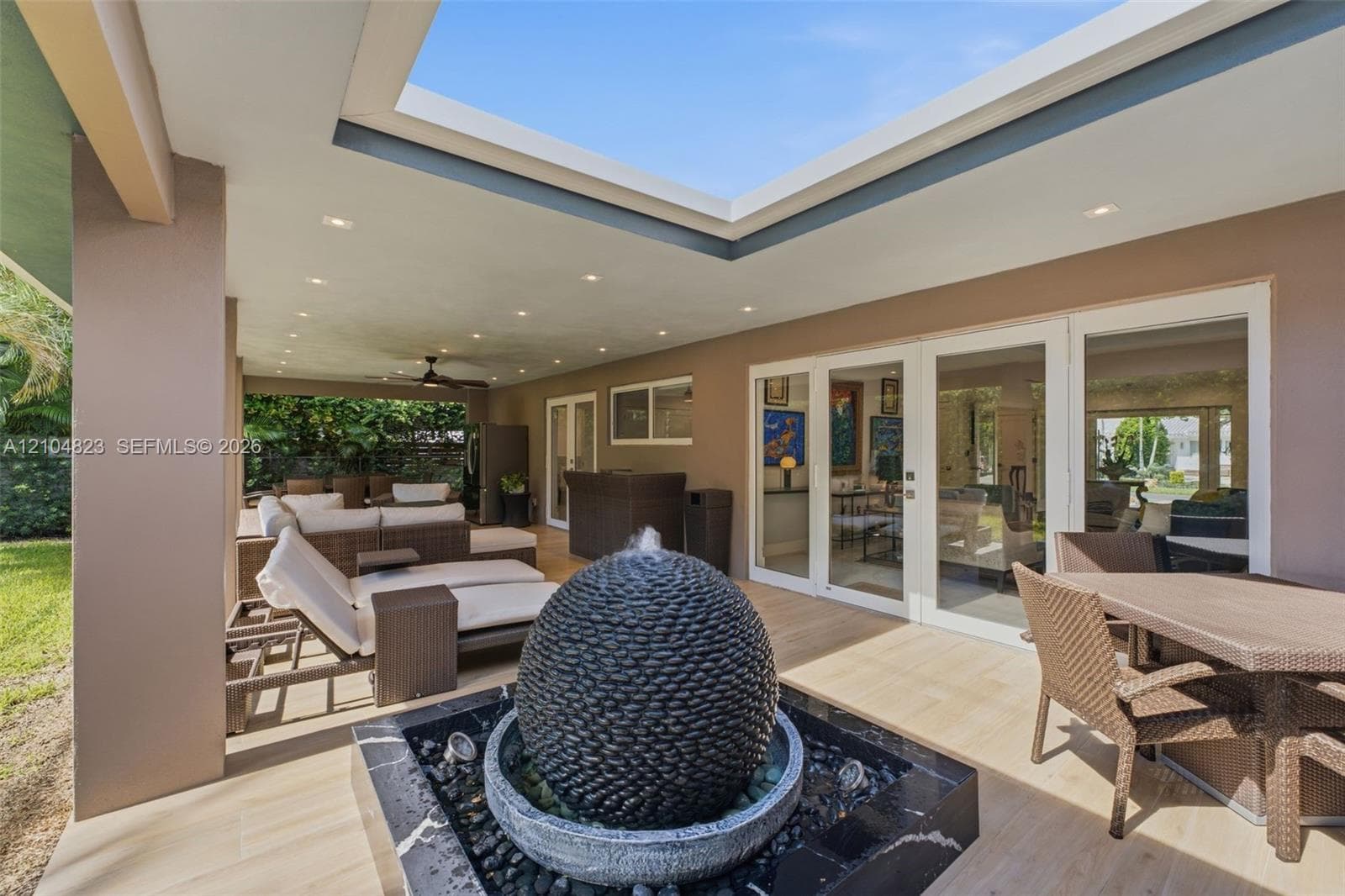 Expansive covered patio featuring an integrated fountain, recessed lighting, and multiple sets of glass panel doors