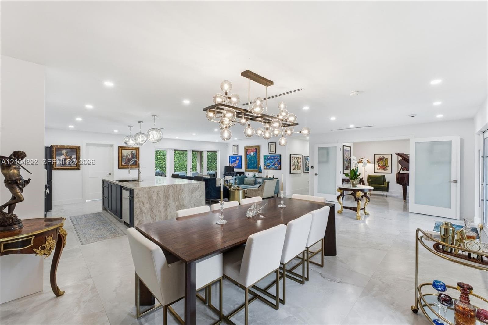 Spacious interior featuring a large kitchen island with a stone countertop, an open-concept layout, recessed lighting, and a modern chandelier