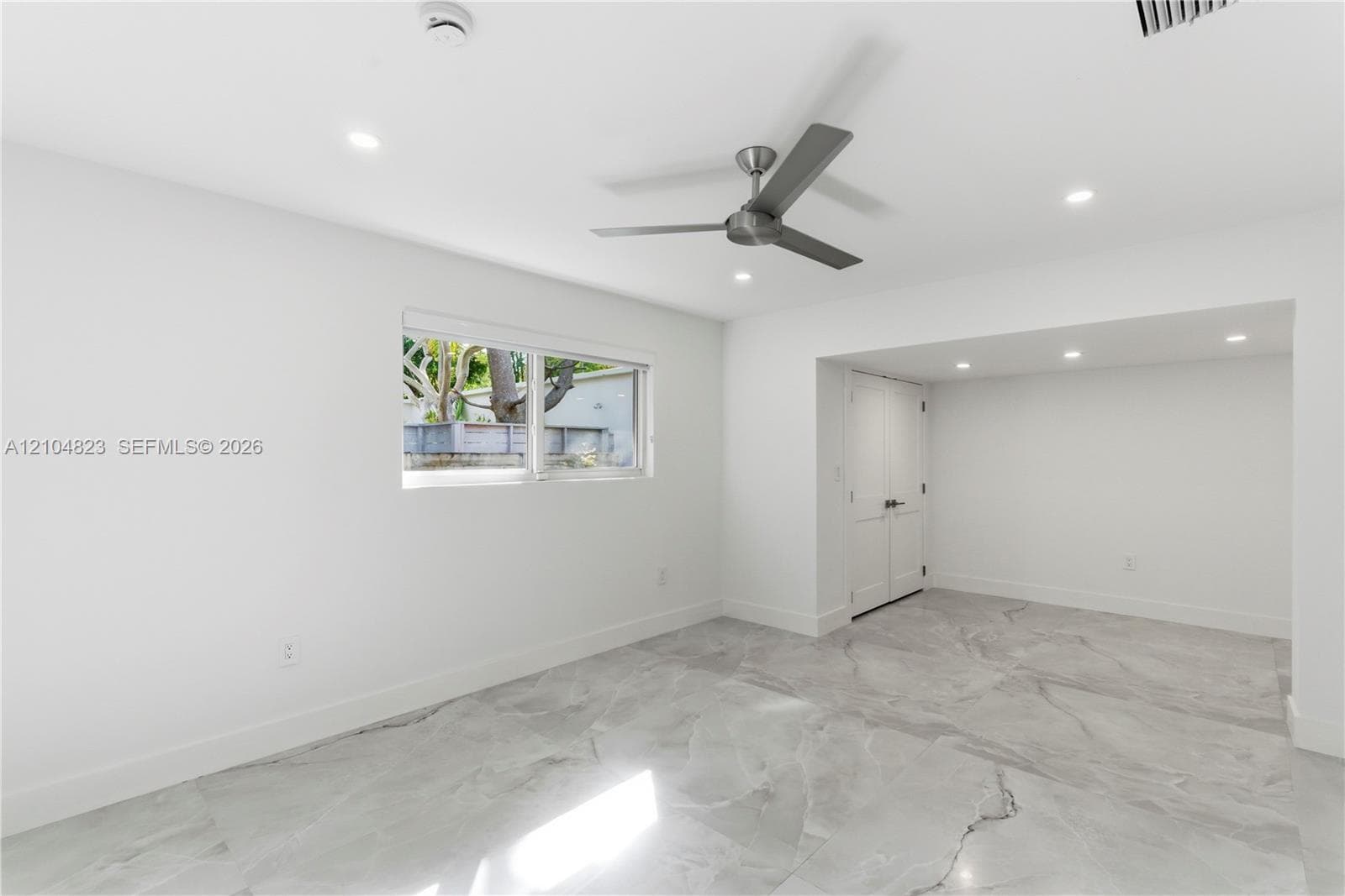 Interior space featuring large-format tile flooring, recessed ceiling lighting, a contemporary brushed-metal ceiling fan, and double-door closet cabinetry