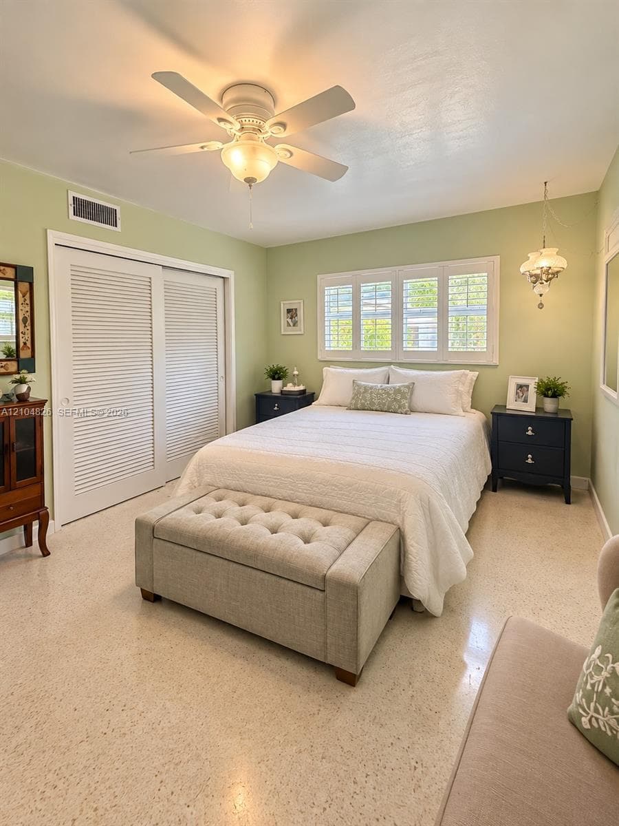 Louvered sliding closet doors, ceiling fan with light fixture, window with plantation shutters, light-colored flooring, and recessed lighting
