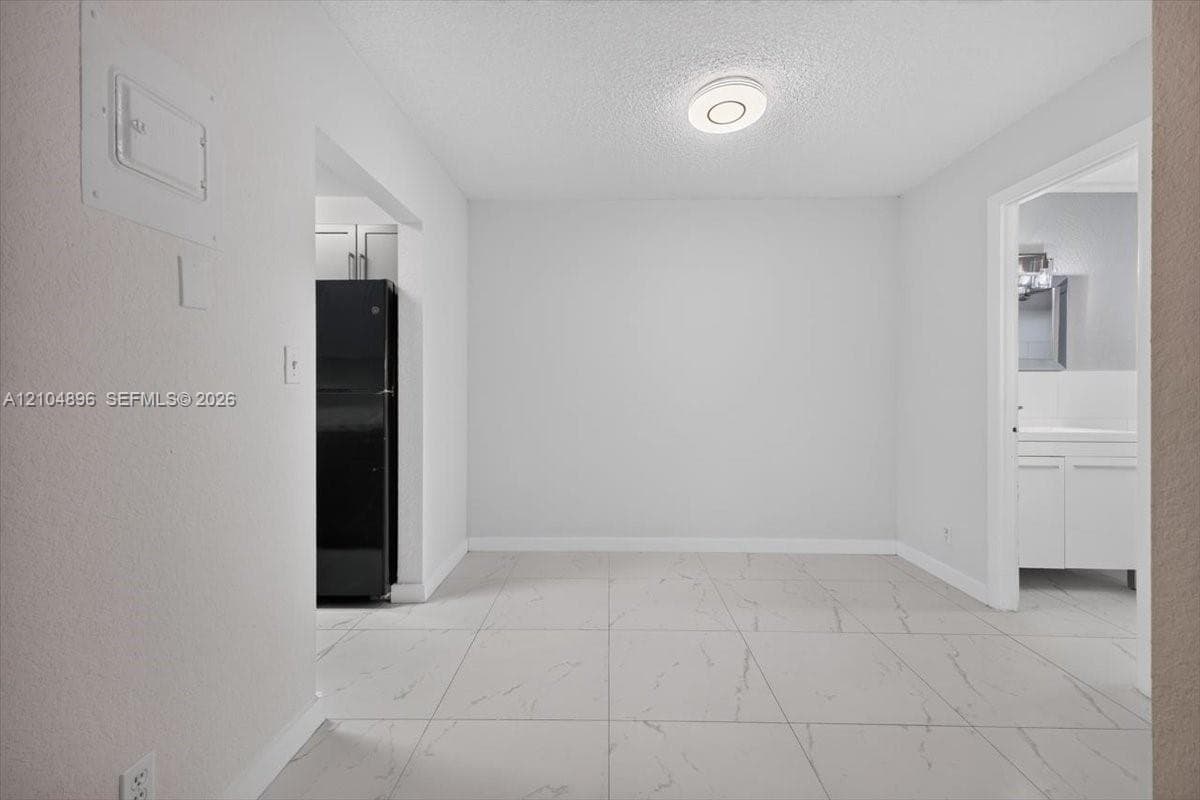 Large-format tile flooring with marble-pattern veining, flush-mount circular lighting fixture, and neutral wall finishes