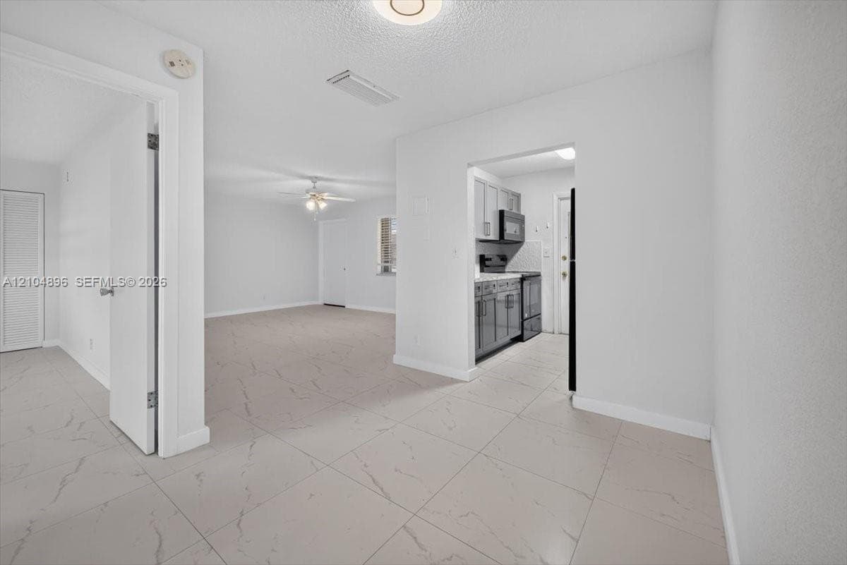 Large-format tile flooring with veining detail, recessed lighting, and a ceiling fan with integrated light fixture