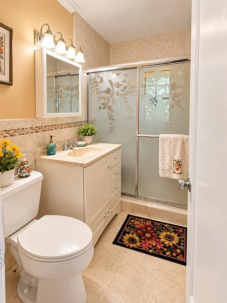 Bathroom featuring a vanity with an integrated basin, a four-light fixture, a mirrored medicine cabinet, and a shower enclosure with frosted glass paneling