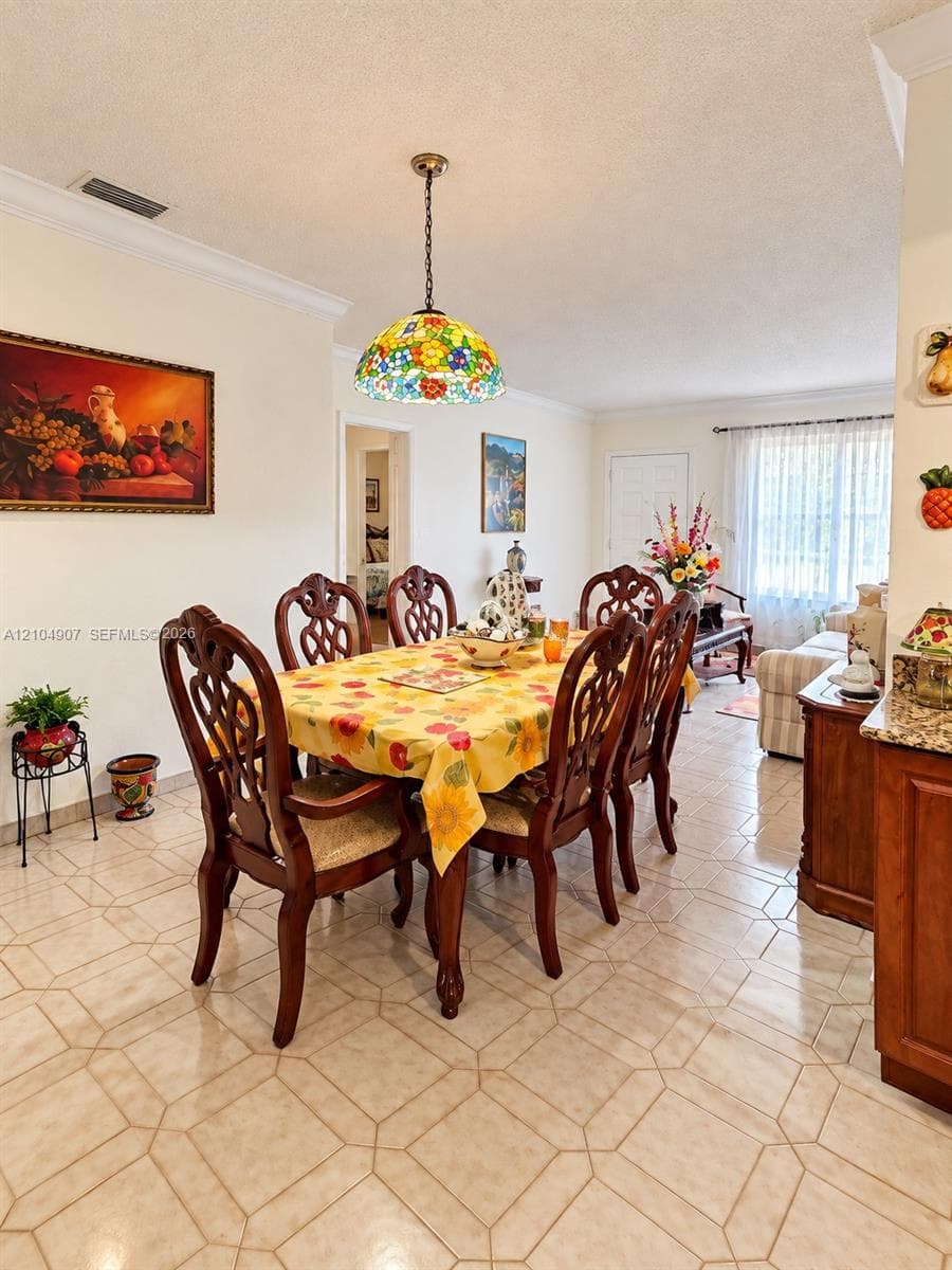 Multi-toned ceramic tile flooring, crown molding, and a decorative stained-glass pendant light fixture