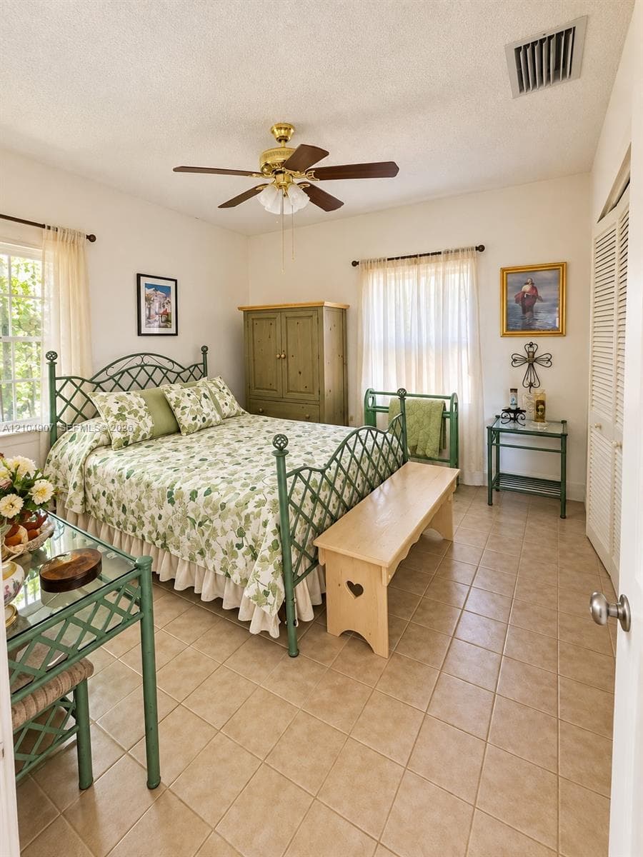 Neutral-toned tile flooring, dual-aspect windows, and a ceiling-mounted light fixture with fan