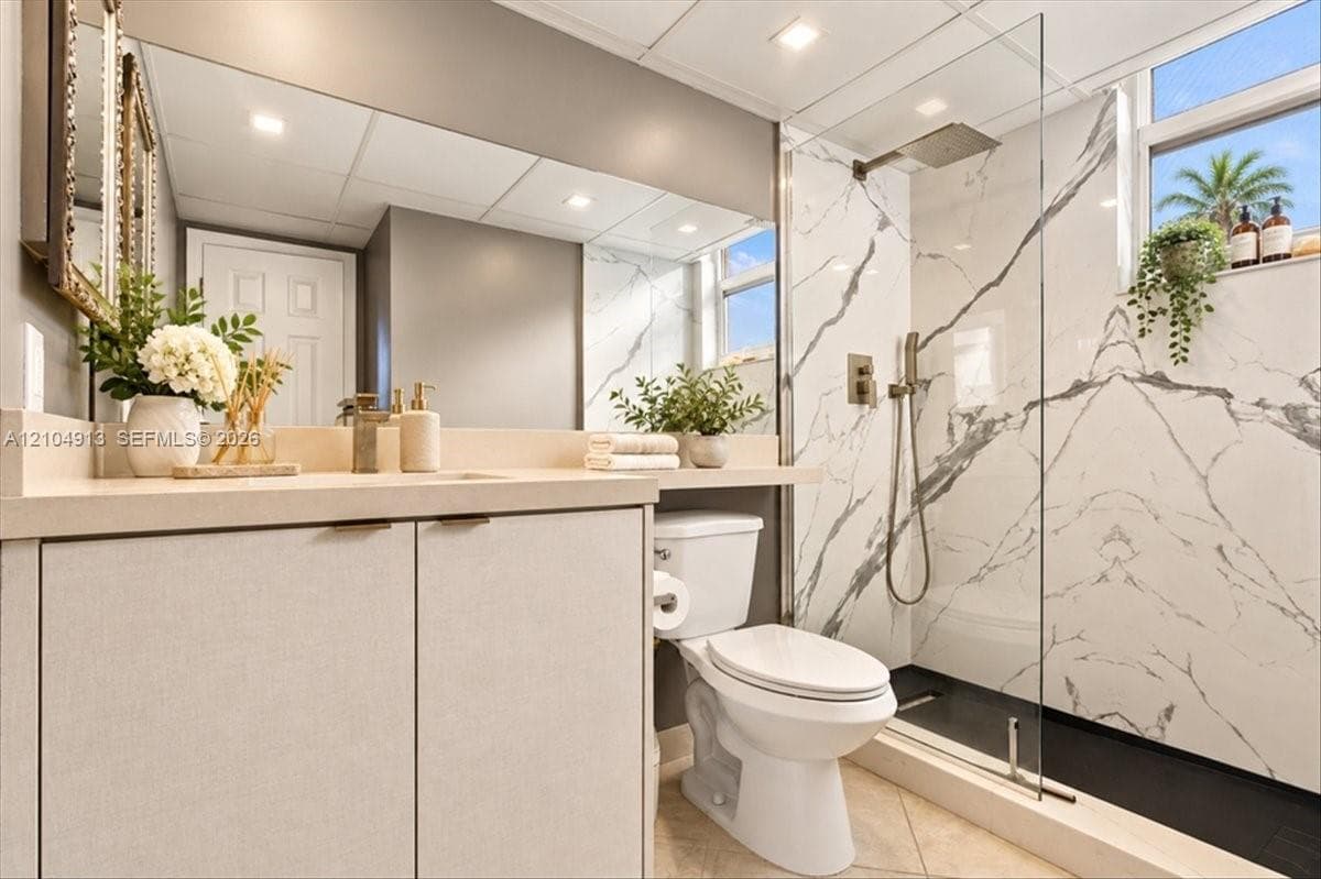 Bathroom featuring a walk-in shower with floor-to-ceiling stone-patterned tile, a glass partition, and a rainfall showerhead