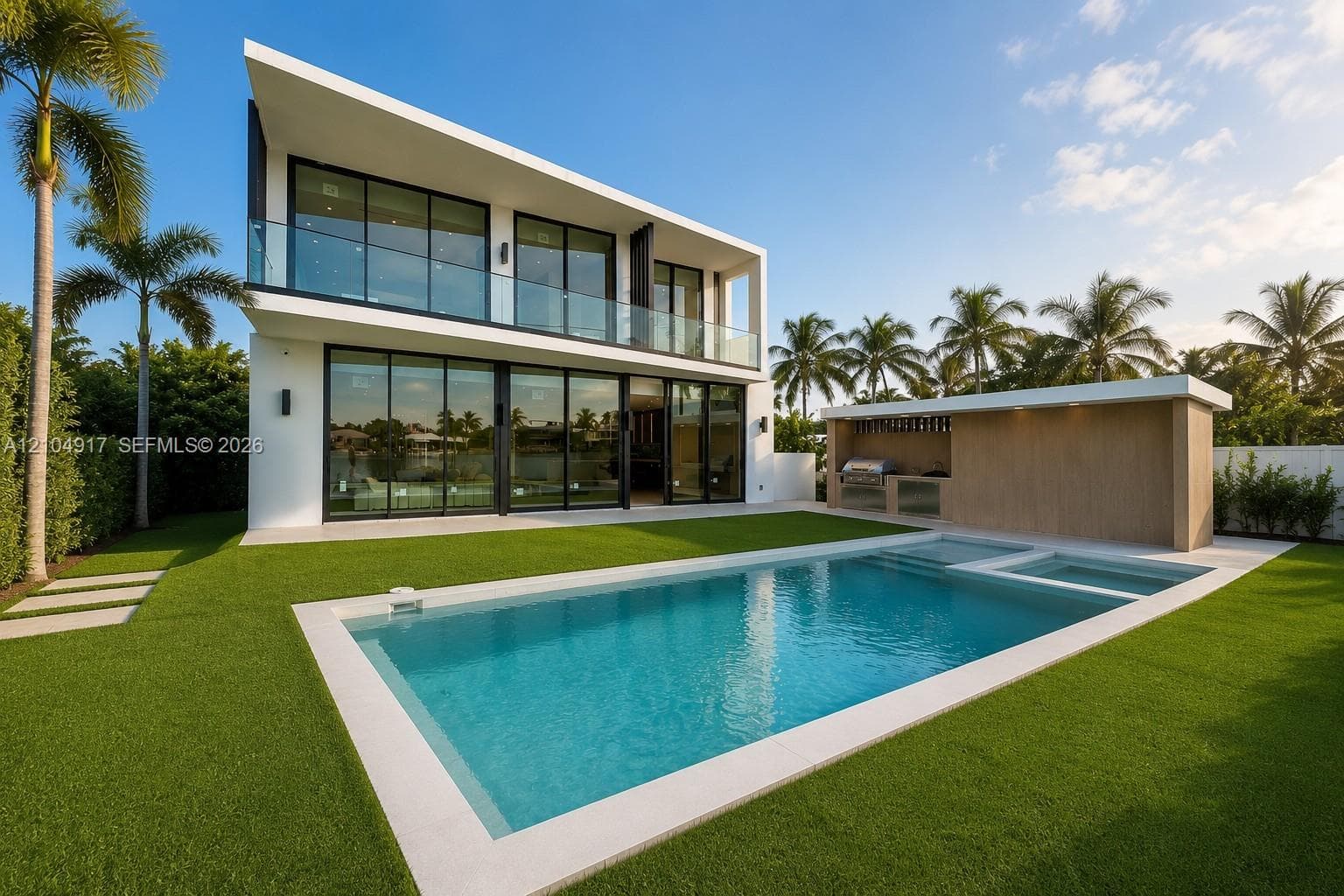 Modern architectural residence featuring floor-to-ceiling glass wall systems, a second-story glass-railed balcony, an in-ground swimming pool, and an outdoor kitchen with integrated grill