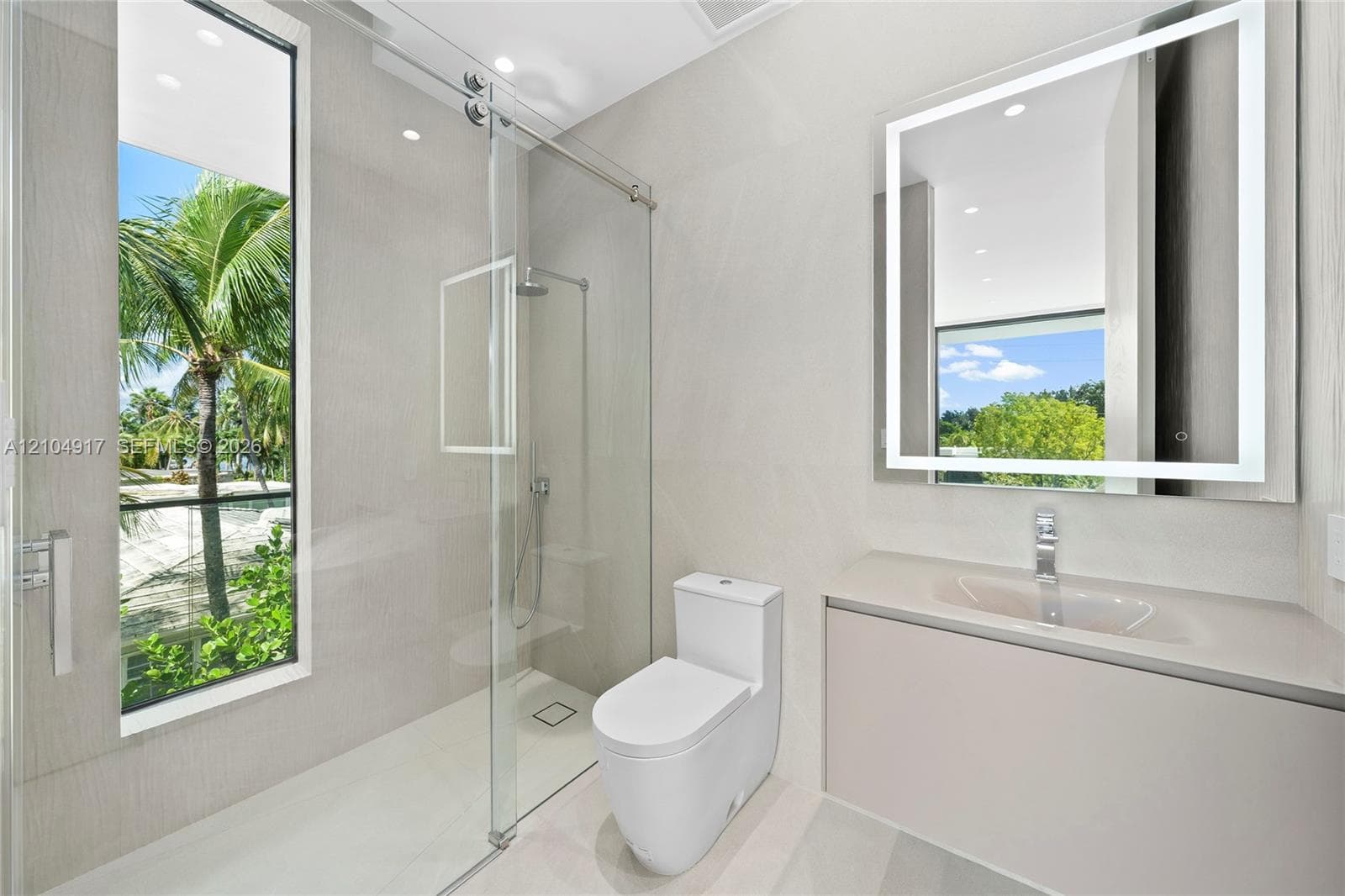Modern bathroom featuring a glass-enclosed shower with a rainfall showerhead, a floating vanity with an integrated sink, and an illuminated mirror