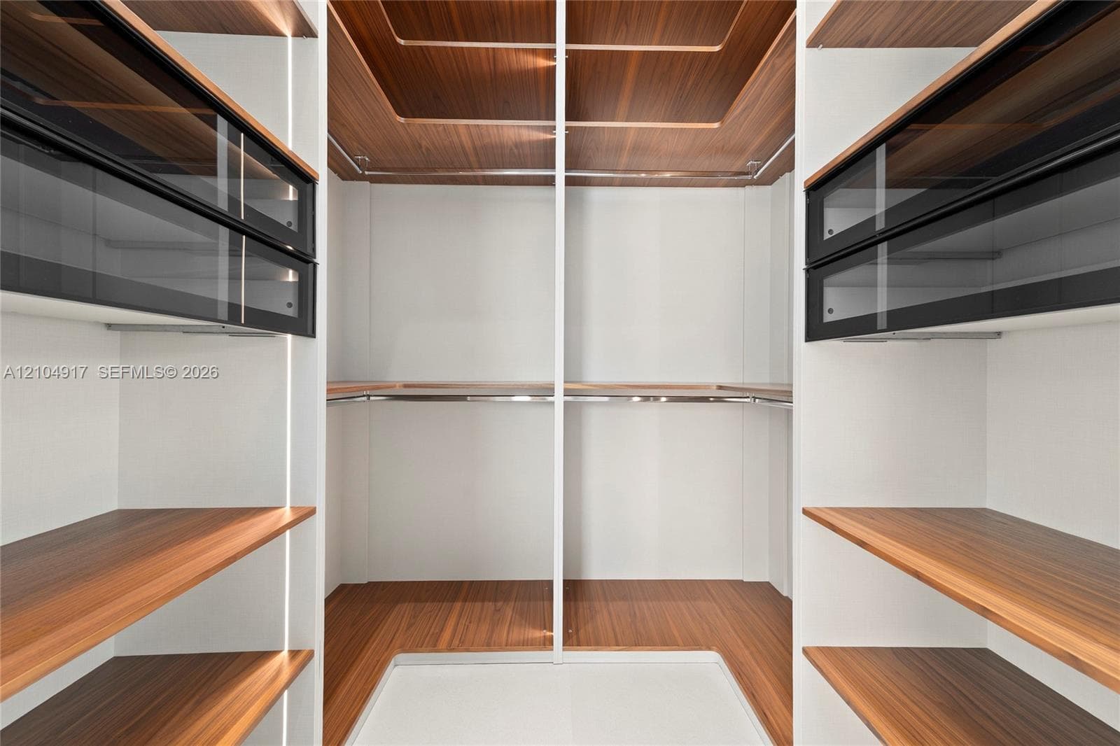 Custom closet system featuring wood-finish flooring, integrated shelving, and glass-front storage drawers